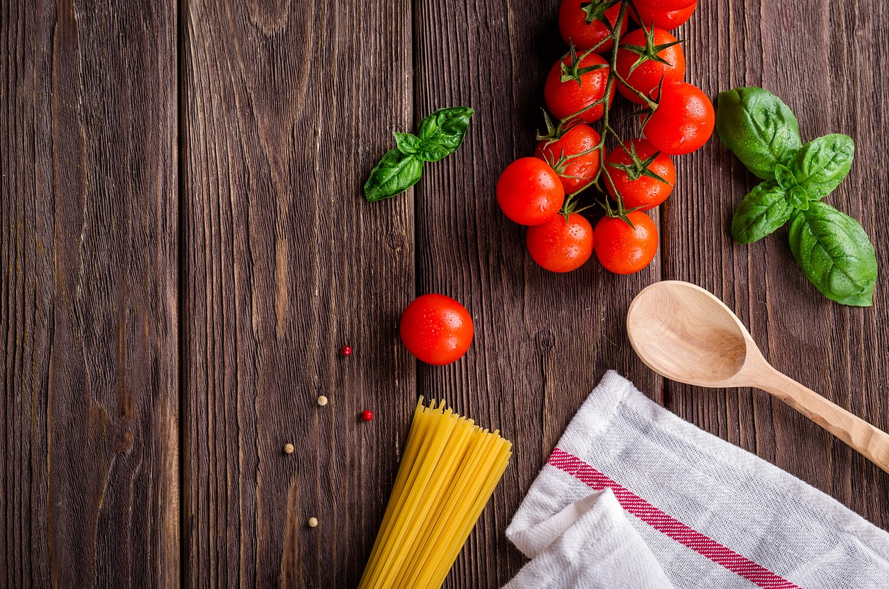 Stock food image with vegetables, uncooked pasta, and a wooden spoon